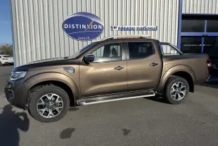 Renault Alaskan brun 2018 en 3/4 avant droit, avec calandre chromée et phares LED visibles, stationné devant un bâtiment.