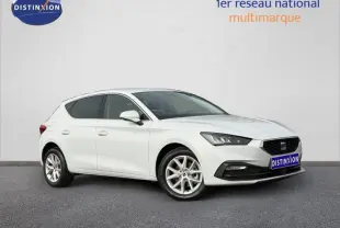 Vue 3/4 avant droite d'une SEAT Leon blanche Nevada métallisée avec jantes alu et calandre noire.