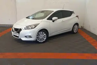 Nissan Micra blanche vue 3/4 avant droit, avec jantes alliage et feux avant distinctifs en intérieur neutre.