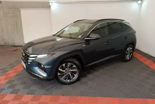Vue 3/4 avant droit du Hyundai Tucson bleu métallisé avec jantes alliage et toit noir dans un garage.