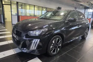 Peugeot 208 hybride noire métallisée vue 3/4 avant droit en intérieur avec jantes alliage bi-tons et feux LED griffés.