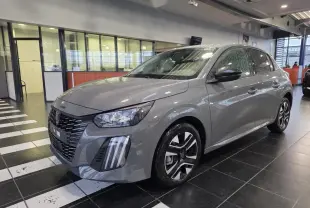 Peugeot 208 gris selenium en 3/4 avant droit, avec calandre noire et jantes alliage bi-ton.