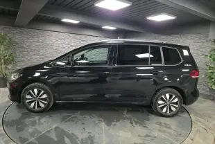 Vue latérale droite d'un Volkswagen Touran noir nacré 2025 avec jantes alliage et badge GOAL à l'arrière.