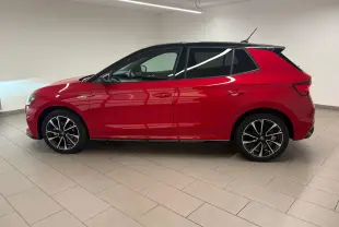 Vue de profil côté gauche d'une Skoda Fabia 2025 rouge Velvet avec toit noir et jantes noires à motifs argentés.
