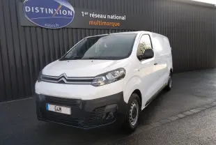 Fourgon Citroën Jumpy blanc en 3/4 avant droit, avec pare-chocs noir et jantes acier, stationné devant un mur gris.