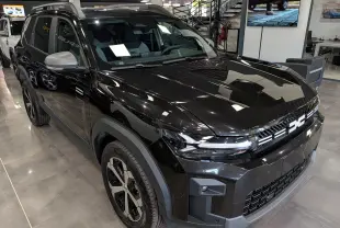 Dacia Bigster noir nacré en 3/4 avant droit, avec calandre distinctive et jantes bicolores en showroom.
