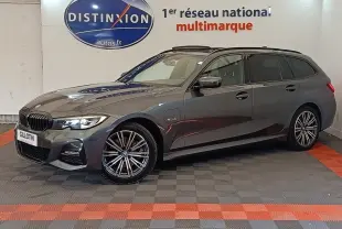 BMW Série 3 320e M Sport gris foncé en break, vue de profil côté droit avec jantes alliage et phares allumés.
