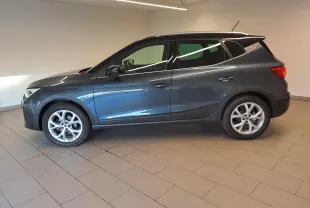 Vue de profil côté gauche du SEAT Arona 1.0 TSI 110 DSG7 FR 2024 en gris magnétique avec toit noir et jantes 18 pouces.
