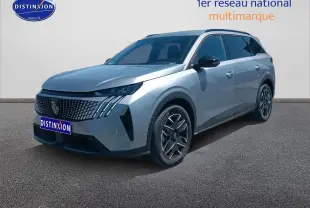 Peugeot 5008 gris artense en 3/4 avant droit, avec calandre distinctive et jantes alu modernes.