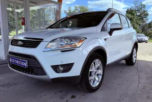 Ford Kuga blanc vue 3/4 avant droit, mettant en valeur ses phares et jantes alliage sous un abri extérieur.