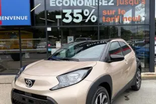 Toyota Aygo X beige vue 3/4 avant droit, avec jantes alliage 17 pouces et détails noirs contrastants.
