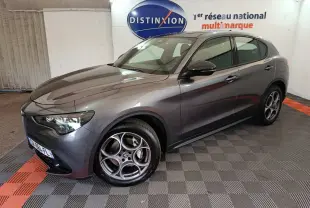 Vue 3/4 avant droite de l'Alfa Romeo Stelvio gris foncé 2024 avec jantes spécifiques et phares LED ellipsoïdaux.