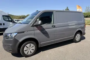 Vue de profil côté gauche d’un Volkswagen Transporter gris clair 2023, fourgon utilitaire avec jantes acier et vitres avant teintées.