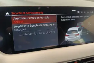 Écran tactile intérieur affichant les options de sécurité avec illustration d’une BMW Série 1 blanche vue de l’arrière.