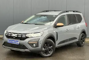 Vue 3/4 avant droite d’un Dacia Jogger gris urbain avec jantes noires et coques de rétroviseurs couleur cuivre.