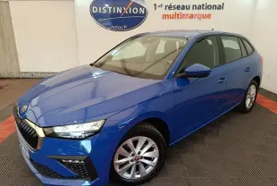 SKODA SCALA 1.5 TSI bleu vue 3/4 avant droit, jantes alliage et calandre chromée visible en intérieur showroom.