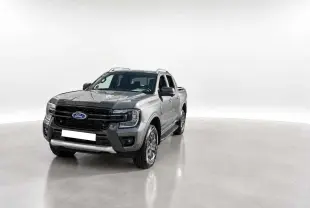 Ford Ranger 2.0 Wildtrak gris carbone en 3/4 avant droit, avec calandre noire et barres de toit visibles.