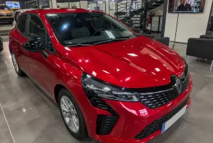 Renault Clio V rouge flamme vue 3/4 avant droit, avec calandre noire et feux LED modernes en showroom.