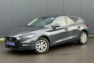 SEAT Leon 1.5 TSI 115 Style gris magnétique en 3/4 avant droit, jantes alliage 16 pouces visibles, stationnée sur sol humide.