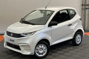 Vue 3/4 avant droite de l'AIXAM AMBITION 0.5 CITY PACK blanche, avec rétroviseur caméra côté conducteur visible.