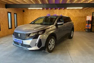 Peugeot 5008 gris en 3/4 avant droit dans un showroom avec éclairage intérieur et mur en bois.