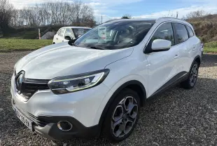 Renault Kadjar blanc vue 3/4 avant droit sur parking, avec jantes alliage distinctives et calandre noire.