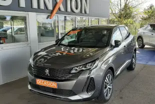 Peugeot 3008 gris platinium en 3/4 avant droit, avec calandre noire et feux LED distinctifs, stationné devant un mur blanc.