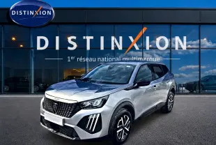 Peugeot 2008 gris en 3/4 avant droit, avec calandre noire et feux LED distinctifs, devant showroom Distinxion.