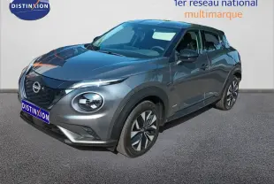 Nissan Juke Hybrid gris squale metal en 3/4 avant droit, avec jantes alliage et calandre noire distinctive.