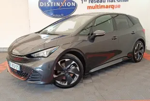 Vue 3/4 avant droite d'une CUPRA BORN gris foncé avec jantes noires et détails cuivrés, stationnée en intérieur showroom.