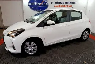 Toyota Yaris blanche vue de profil côté gauche dans un showroom avec logo Distinxion en arrière-plan.
