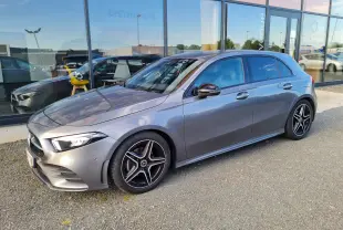 Mercedes Classe A 180 AMG Line gris vue 3/4 avant droit, avec jantes AMG noires et vitres teintées.