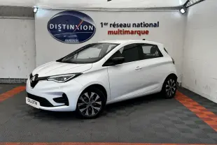 Renault ZOE Iconic R135 blanc vue 3/4 avant droit, avec jantes spécifiques et phares LED allumés.