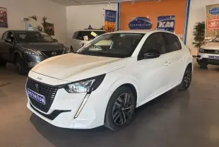 Peugeot 208 blanc banquise vue 3/4 avant droit en intérieur, avec calandre noire et feux LED distinctifs.