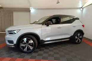 Vue de profil côté gauche d'un Volvo XC40 P8 R-Design gris clair dans un garage avec jantes noires et toit noir.