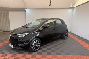 Renault ZOE noire vue 3/4 avant droit, avec jantes alliage et phares LED dans un garage éclairé.