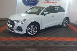Audi Q3 blanc en vue de profil côté gauche, hybride rechargeable avec jantes alliage et calandre marquée S Line.
