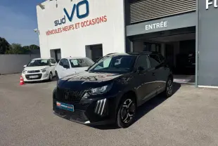 Peugeot 2008 Hybrid noir en 3/4 avant droit, avec barres de toit et jantes alliage 17 pouces, devant un garage.