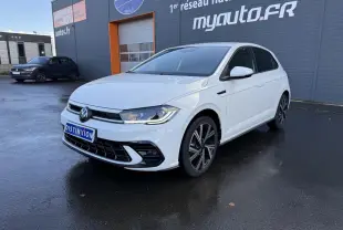 Volkswagen Polo blanc pur vue 3/4 avant droit avec jantes alliage et calandre R-Line devant un bâtiment gris.