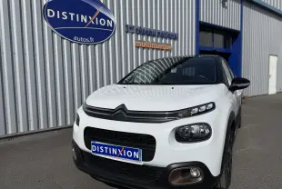 Citroën C3 1.2 PureTech 83 Origins blanc toit noir vue 3/4 avant avec calandre et phares distinctifs.