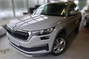 Vue 3/4 avant droite d'un Skoda Kodiaq gris clair 2023 en intérieur avec calandre noire et jantes argentées.