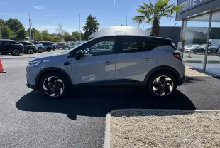 Profil côté gauche d'un Renault Captur gris Rafale avec toit noir, roues noires à jantes 18 pouces biton, stationné en extérieur.