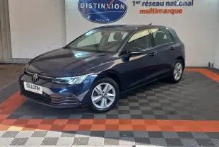 Volkswagen Golf bleu vue 3/4 avant droit, avec jantes alliage et phares LED, en intérieur showroom.