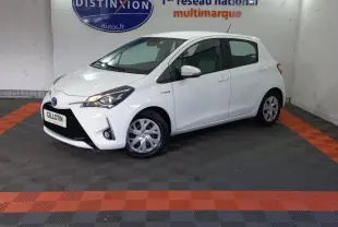 Toyota Yaris hybride blanche vue de profil avant droit dans un showroom avec logo Distinxion en arrière-plan.