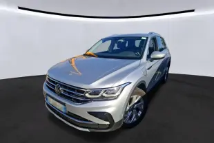 Vue 3/4 avant d'un Volkswagen Tiguan gris clair hybride rechargeable, avec calandre chromée et phares LED visibles.
