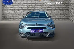 Vue de face d'une Citroën C4 bleu clair 2021 avec calandre distinctive et phares modernes, sur fond de mur en briques.