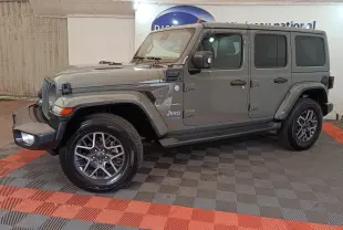 Jeep Wrangler Sahara gris foncé vu de profil côté gauche, avec jantes alliage et toit fermé.