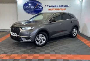 DS7 Crossback gris foncé en 3/4 avant droit, avec calandre distinctive et jantes alliage visibles en intérieur showroom.
