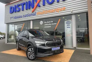 SUV Skoda Kodiaq noir métal vu en 3/4 avant droit devant un showroom Distinxion avec calandre marquée.