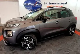 Vue 3/4 avant droit d'un Citroën C3 Aircross gris foncé avec jantes distinctives et barres de toit noires.